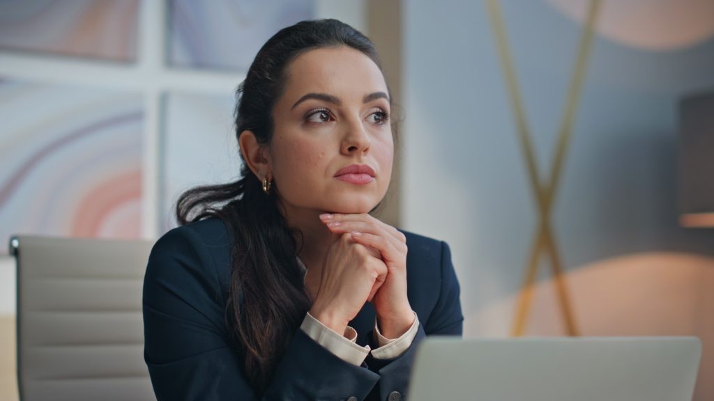 Successful manager thinking business idea at desk closeup. Smiling woman executive looking camera pondering corporate tasks in office portrait. Confident happy businesswoman posing at private cabinet